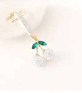 Détail du porte-clés cerise avec strass étincelants et feuilles en cristal vert sur cuir