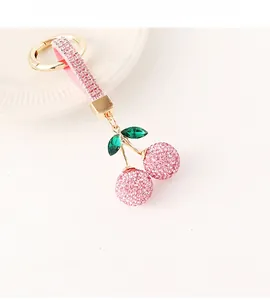 Détail de porte-clés cerise en strass roses avec feuilles vertes et finitions dorées
