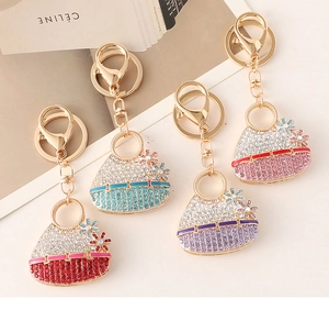 Close-up of four rhinestone handbag keychains in red, blue, purple, and pink with gold finish