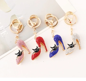 Detalle de cuatro colgantes de tacón con pedrería de colores y gato en llaveros dorados