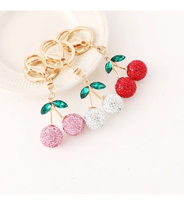 Détails de trois porte-clés cerises en strass scintillants en rose, blanc et rouge
