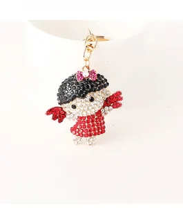 Détail d'un porte-clés fille de dessin animé avec strass rouges et blancs et fermoir doré