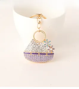 Macro shot of a floral diamond-encrusted mini bag keychain with blue and purple crystals