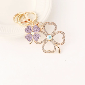 Exquisite gold clover keychain with purple rhinestones and luxury lobster clasp on white background