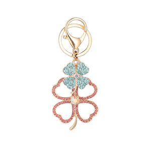 Golden clover keychain with sky blue and pink rhinestones on a clean white background