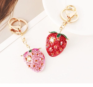 Close-up of strawberry keychains with red and pink crystals and gold-plated alloy