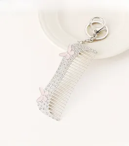 Close-up of silver comb keychain with white rhinestones and pink butterflies