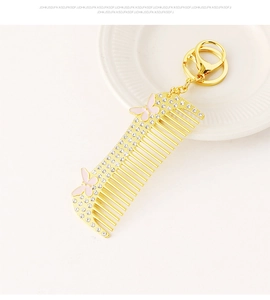 Detail of a vintage golden comb keychain with sparkling rhinestones and pink butterflies