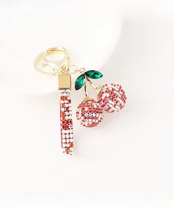 Close-up of cherry keychain with red rhinestones and gold-plated clasp on a plate