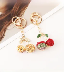 Detailed macro of crystal-encrusted cherry keychain and gold heart pattern pendant