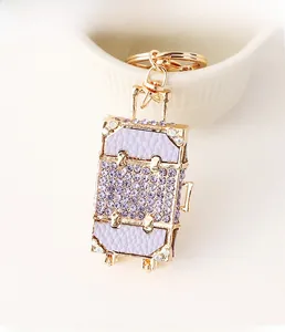 Detailed view of luxury gold luggage keychain with purple leather and rhinestones