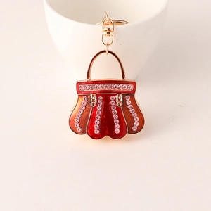Detailed macro view of red enamel handbag keychain with pink crystals and gold-tone finish