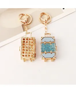 Close-up of golden hollow suitcase keychain and blue rhinestone suitcase bag charm set