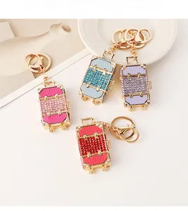 Detailed view of four colorful rhinestone suitcase keychains with gold metal hardware