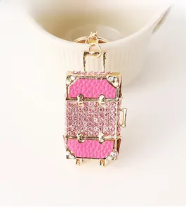 Close-up of pink rhinestone suitcase keychain with golden metal trim and leather detail