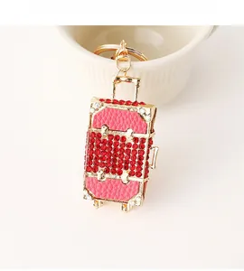 Close-up of a pink leather mini suitcase keychain with luxury red rhinestones