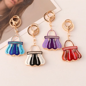 Detailed view of colorful enamel handbag keychains with crystals on a beige surface