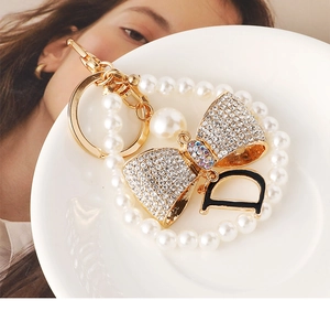 Detail of luxury pearl keychain with crystal bow and gold metal letter D pendant