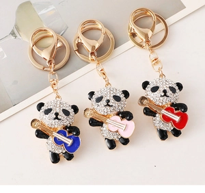 Detailed view of three guitar-playing panda keychains with sparkling rhinestones and gold plating