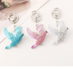 Detailed view of three rhinestone bird keychains in blue, purple, and silver colors