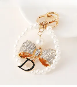 Close-up of pearl bead ring with rhinestone bowknot and black letter D pendant charm