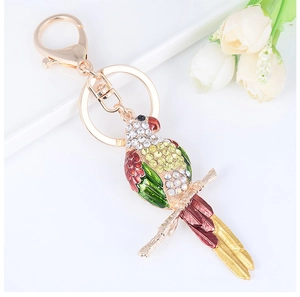 Détails macro d'un porte-clés perroquet orné de cristaux et ailes en émail coloré