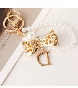 Detail of gold keychain with white pearls, bow knot and a metallic letter D pendant
