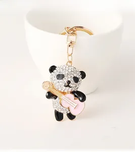 Detailed close-up of a sparkling panda keychain with crystal rhinestones holding a pink guitar