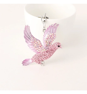Close-up of pink crystal bird keychain with sparkling rhinestones on a white cup