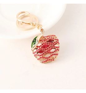 Detail of red and green rhinestone apple keychain with golden hollow metal design