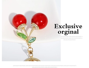 Détail d'un porte-clés cerise avec des fruits rouges brillants et des feuilles strass