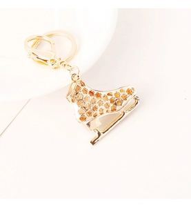 Close-up of golden ice skate keychain with hollow flower pattern and lobster clasp