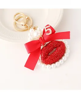 Close-up of red rhinestone lips, pearl chain, and number 5 pendant keychain