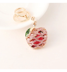 Detailed close-up of a golden apple keychain with pink rhinestones and a lobster clasp