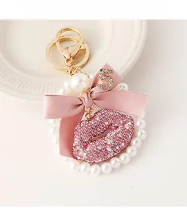 Detail of pink crystal lip keychain with satin bow, white pearls and gold metal number 5