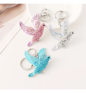 Detail of bird shaped crystal keychains in pink, blue, and silver with metal rings