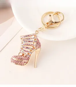 Detailed close-up of golden stiletto shoe keychain with pink rhinestones on a white plate