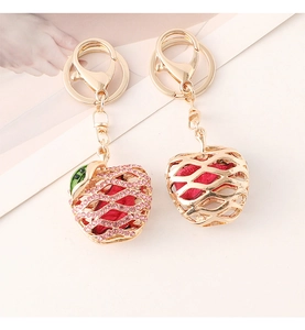 Detailed view of pink rhinestone-studded and gold-finish apple-shaped keychains