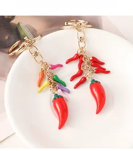 Detailed view of handmade red chili pepper keychains in a white ceramic dish