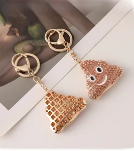 Détail de porte-clés émoji crotte dorés avec strass marron brillants et fermoir mousqueton