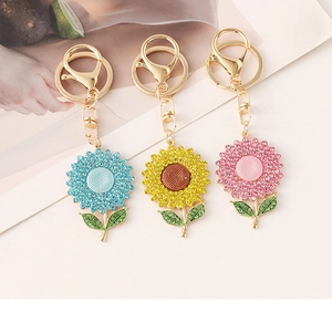Three colorful sunflower keychains with crystals in blue yellow and pink on a desk