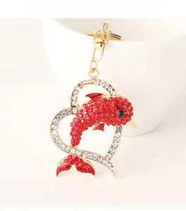 Detail of dolphin heart keychain with red and clear rhinestones on golden base