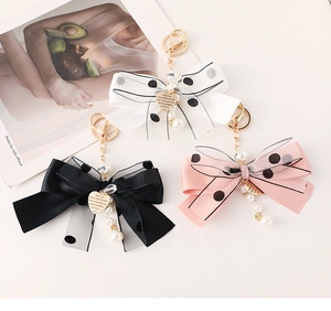 Detail of mesh bow keychain with gold heart pendant and pearl strap in three colors