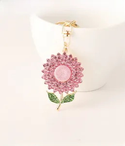 Detail of pink crystal sunflower keychain with gold metal frame hanging on a white cup