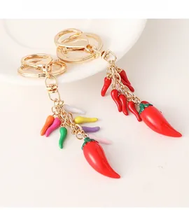 Macro detail of handmade red chili pepper keychains with golden lobster clasps and charms