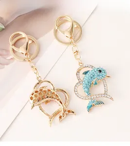 Detail of dolphin heart keychains featuring blue rhinestones and gold hollow patterns