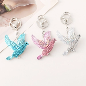 Glittering crystal peace bird keychains in blue, pink, and silver metallic finishes