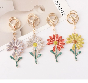 Close-up of four crystal-encrusted daisy keychains in purple, white, red, and yellow