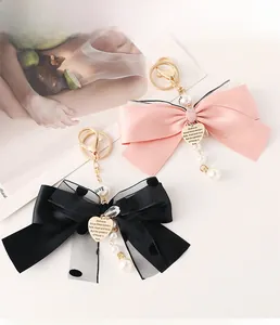 Detail of elegant mesh bow keychain with pearl tassel and heart-shaped pendant charms