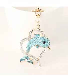 Macro shot of dolphin heart keychain with blue crystals on a golden metal base